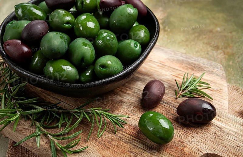 Chalkidiki olives, classic Greek green olives, in a bowl on a cutting board, top view, without people