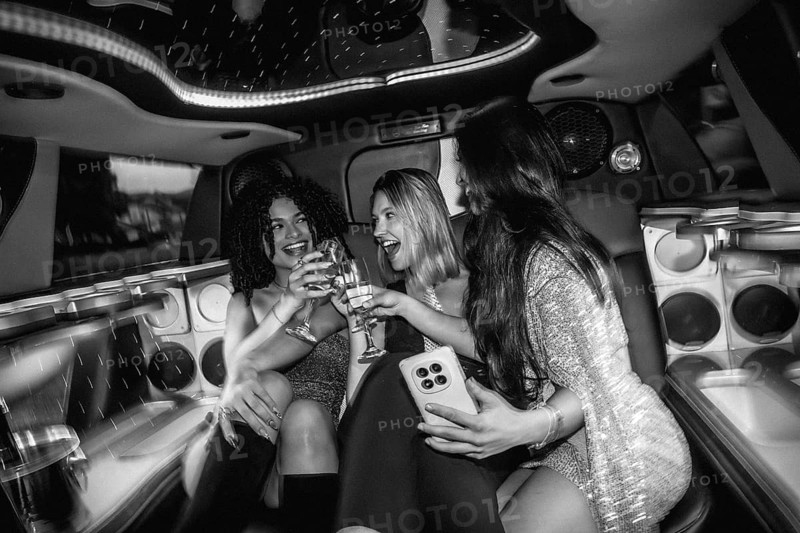 Young diverse women celebrating a special occasion, drinking champagne, and enjoying a fun night out, creating a dynamic scene in the back of a luxury limousine