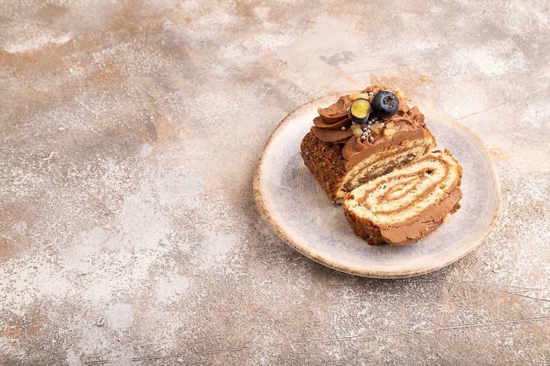 Sweet loaf with cream and caramel, on brown concrete background, copy space, side view