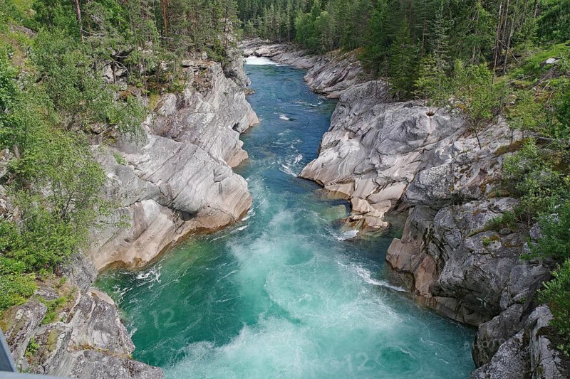 A turquoise river flows through a rocky gorge surrounded by green forests, rafting, Sjoa, Vinstra, Norway