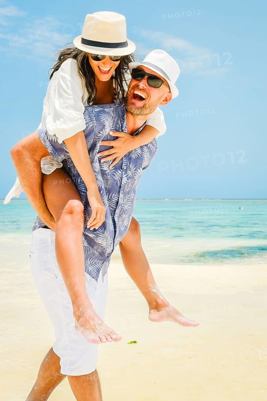 Heterosexual caucasian couple in love walk on white sand beach shore turquoise ocean water global tropical island resort destination summer day travel vista.Zanzibar