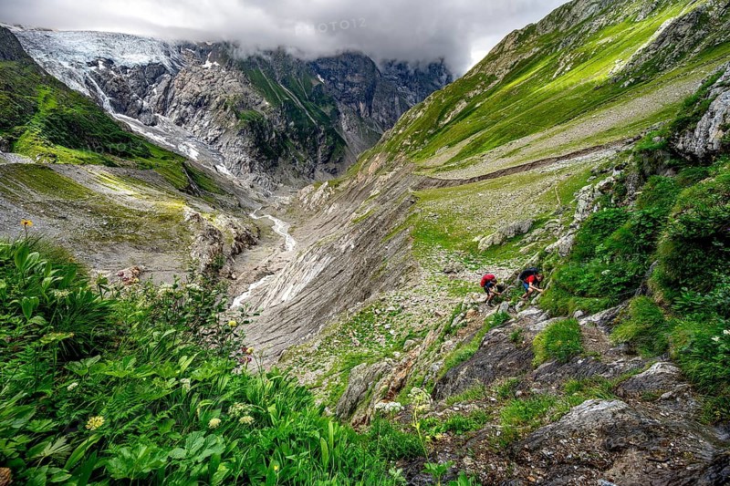 Two mountaineers on a hiking trail, dramatic mountain landscape with Grindelwald-Fiescherfirn glacier, Bernese Alps, Bernese Oberland, Switzerland