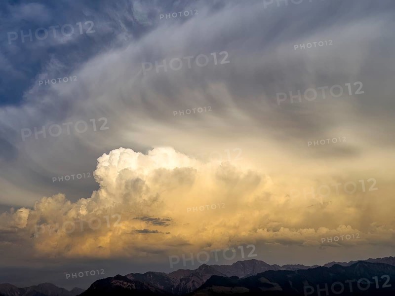 Evening sky at sunset with high strip-shaped cloud formations oriented in the form of arrows such as arrows in the shape of arrows indicate strong wind or weather changes on the edge of Alpine mountains, including Cumulus cluster clouds, Bavaria, Germany