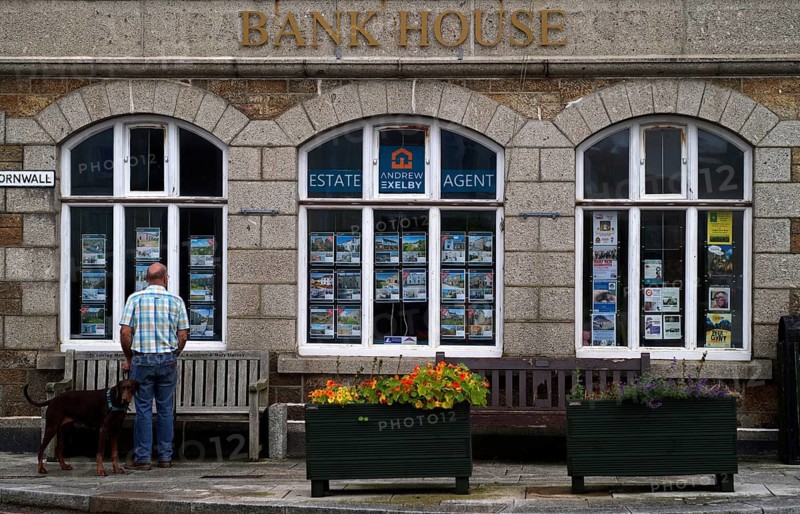 Man standing with his dog in front of Bank House, former bank, now real estate agent, St Just in Penwith, Cornwall, England, Great Britain
