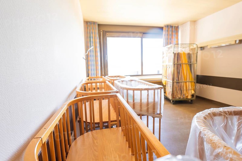A bright room with several wooden cribs near a large window, Obstetrics, Nagold, Germany