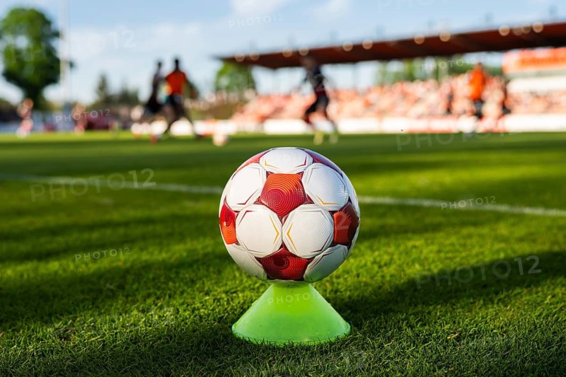 Soccer ball on a training cone near the touchline during a football match with players and stadium blurred in background in Glogow, Poland