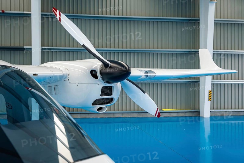Propeller airplane parked inside a brightly lit aerospace hangar, representing concepts like aviation technology, engineering, maintenance, and innovation
