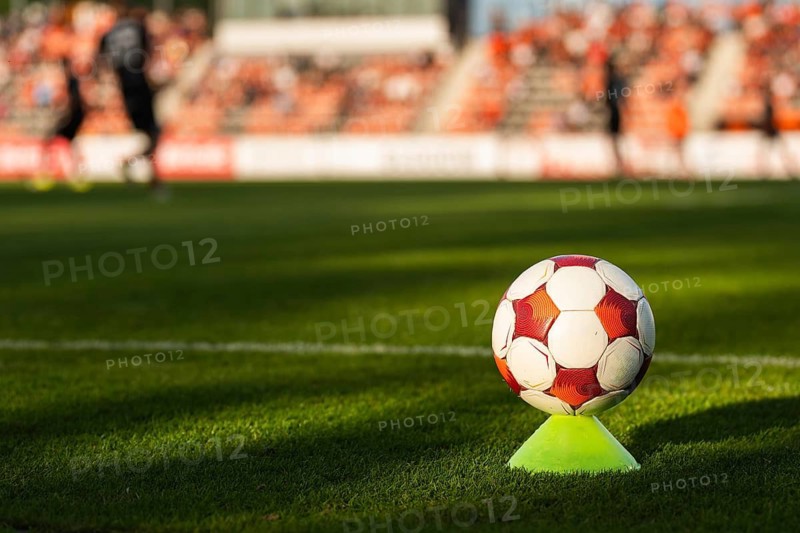Soccer ball on a training cone near the touchline during a football match with players and stadium blurred in background in Glogow, Poland