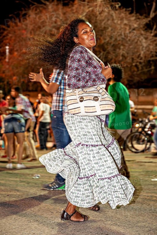 Dancing woman in moving skirt surrounded by a cheerful group at night, joy and dancing at a festival in Petrolina in Brazil
