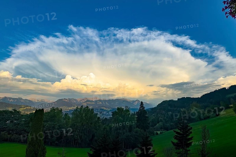 Hair dryer cloud dissolving over the edge of the Alps during a heat period during sunset, Bavaria, Germany