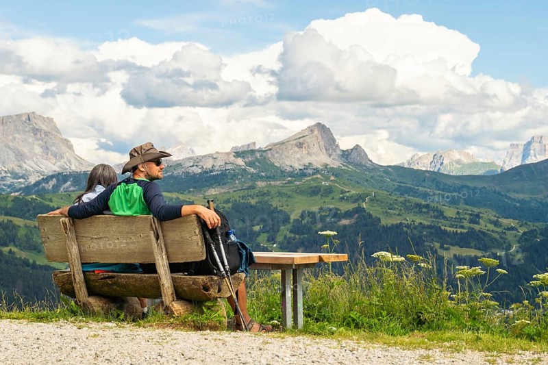 Active couple taking a hiking break sitting on bench relaxing in nature. Wellbeing and outdoors