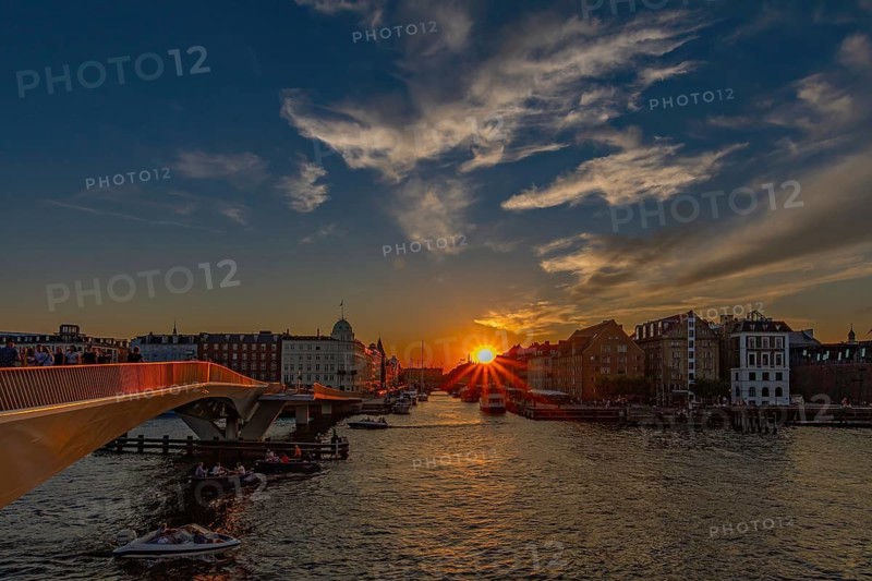 Sonnenuntergang über einem Fluss mit Brücken, Booten und malerischem Himmel, Kopenhagen, Dänemark, Nyhavn