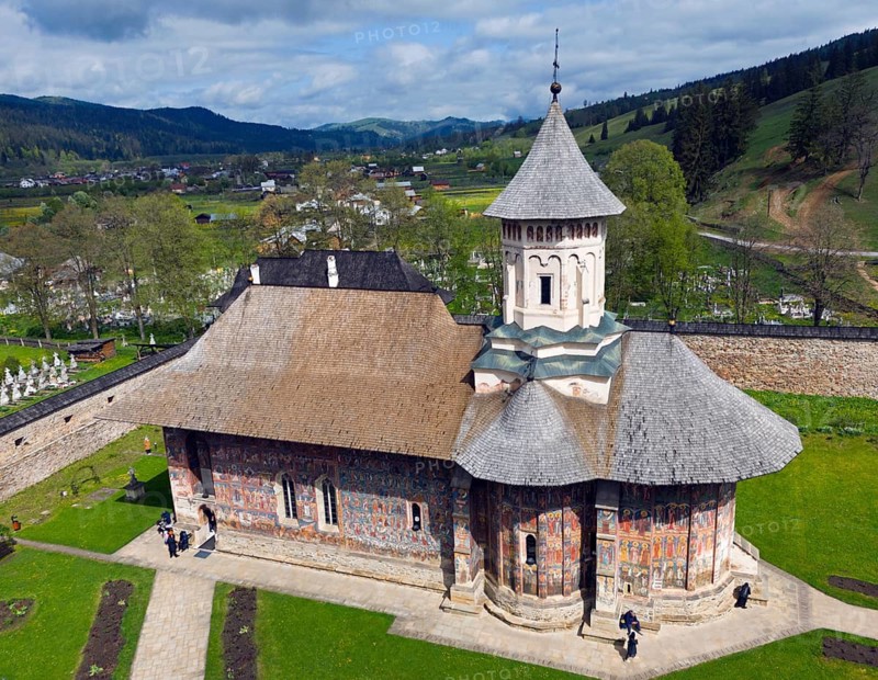 Close-up of a church with painted walls standing on a green area against a mountain backdrop, aerial view, Moldovita Monastery, Moldovita, UNESCO World Heritage Site, Suceava County, Bukovina Region, Romania