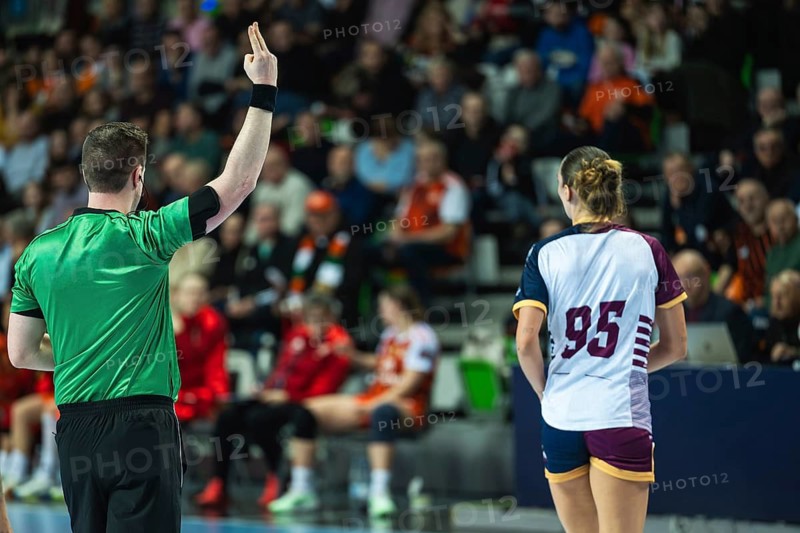 A handball referee showing a two-minute suspension sign with fingers during a high-stakes professional sports game in Lubin, Poland