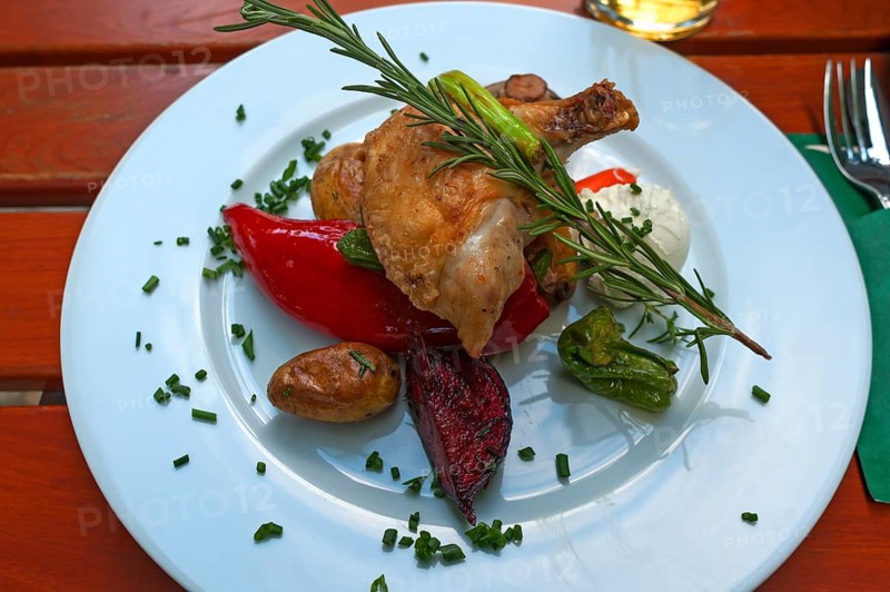 Chicken leg with fresh vegetables, garnished with a rosemary sprig