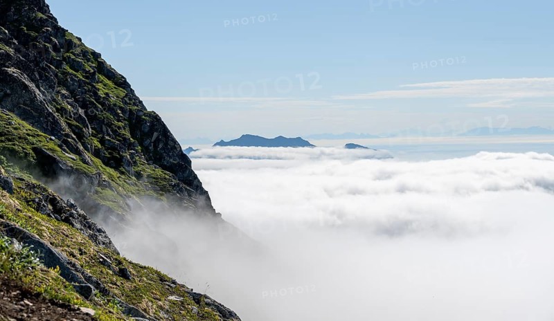 Mountain peaks above the clouds, mountain landscape and sea, view from the summit of Stornappstinden, Lofoten, Nordland, Norway