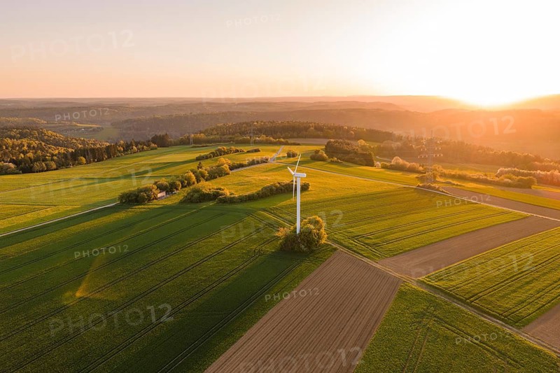 Wide green fields with a single wind turbine, brilliant sunset, hilly landscape in the background, Jettingen, Germany