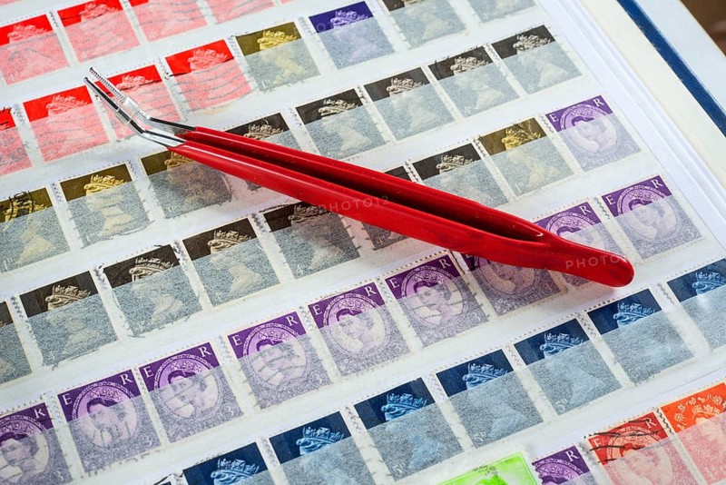 Philately, tweezers on album page with English stamps
