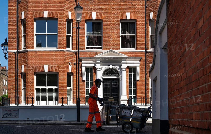 A street cleaner pushes a wheelbarrow with trash containers, in the background a red brick building, Chelsea, London, Great Britain, England, Great Britain
