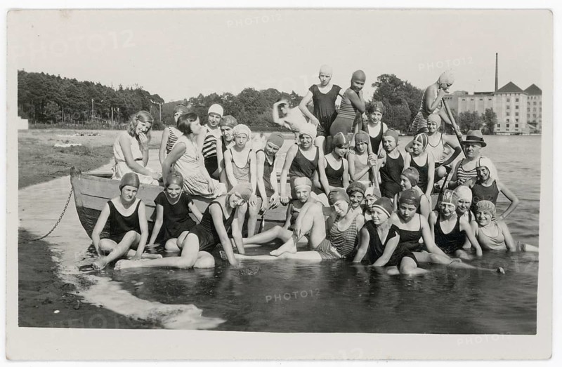 Bathing, swimwear, woman, men, children, leisure, fun, summer, boat, lake, group in bathing suits sitting and standing by the water in front of a large building, 1932