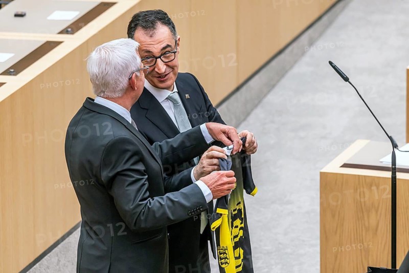 After the vote and in front of the swearing-in ceremony, there were gifts. Thomas Strobl, CDU, President of the State Parliament, presents the new Minister President with a running shirt in the colours and with the coat of arms of the state of Baden-Württemberg. Cem Özdemir (Bündnis90-Die Grünen) is the new Minister President of Baden-Württemberg. Stuttgart, Baden-Württemberg, Germany