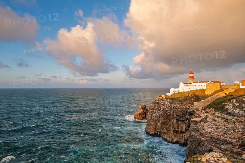 View of the Lighthouse of Cabo de Sao Vicente in Sagres, Algarve, Portugal, at sunrise with Atlantic ocean, cliffs, and distant lighthouse view