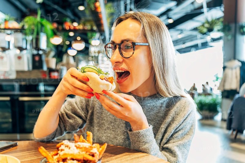 Happy Young Woman About to Bite into a Steamed Bao Bun in a Cozy Cafe