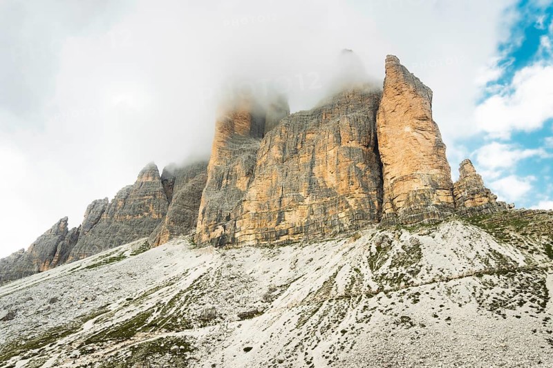 Dramatic misty Tre Cime di Lavaredo area. Dynamic clouds after rain move over the rugged limestone peaks of the Italian Dolomites. Three sisters circular loop popular trail summer