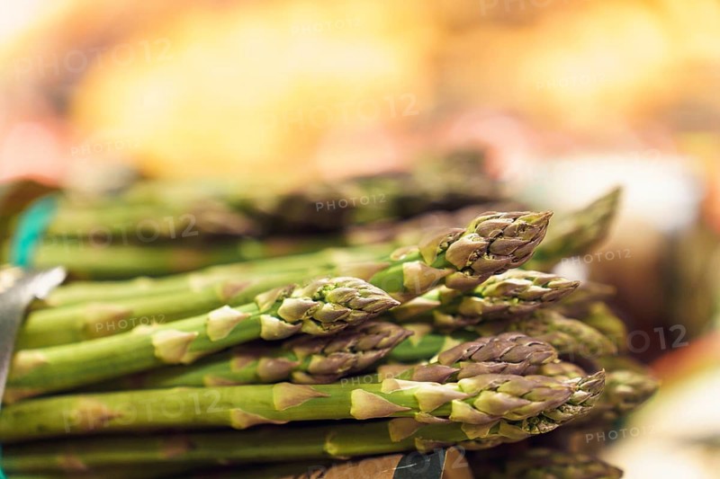Close-up of bunches of green ripe asparagus on counter at market or grocery store in vegetable section