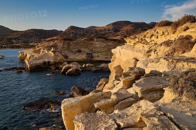 Coastal scene in warm golden hour light with rocky foreground, Aspragremna, White Cliffs, Mavorspilia Beach, Kimolos Island, Kimolos, Cyclades, Greek Islands, Greece