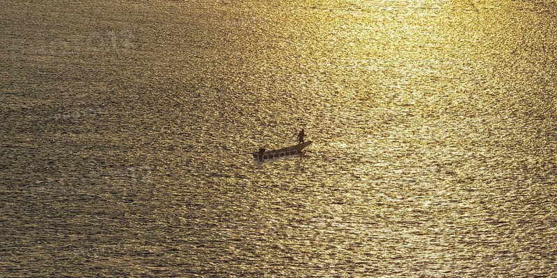 Fisherman with longtail boat (Thai: Ruea Hang Yao) at sunrise, Mekong between Thailand and Laos