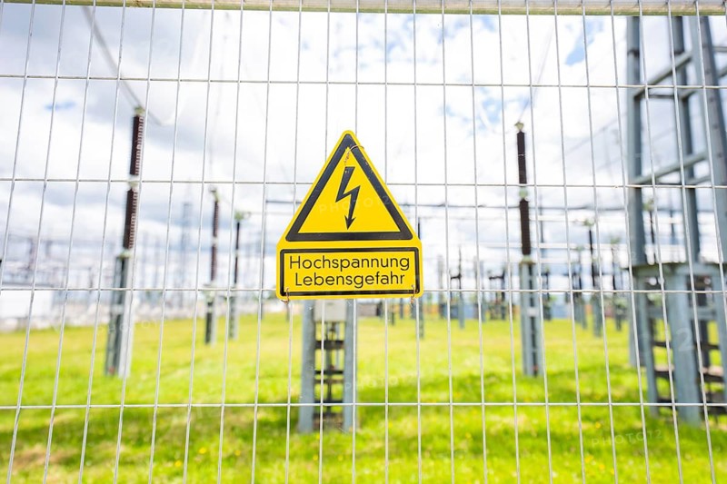 A high-voltage warning sign on a fence in a green area of the substation, Transnet BW Open Construction Day, Jettingen, Germany