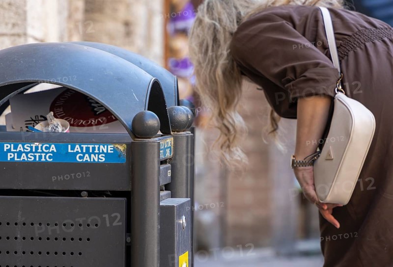 Overcrowded trash bins and trash cans in the small alleys of the Tuscan city of Pienza, Italy