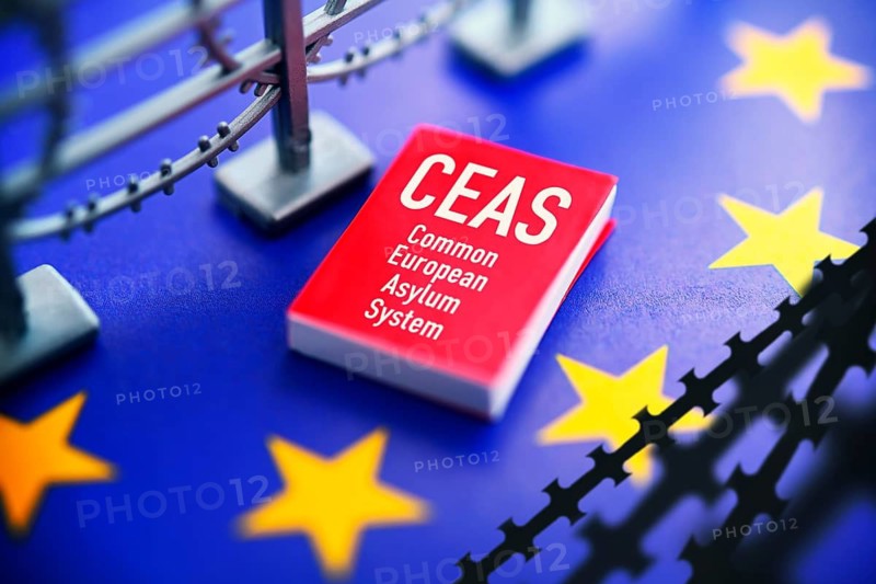 Book with CEAS lettering on EU flag with barbed wire, European asylum reform, photo montage +++ editorial use only