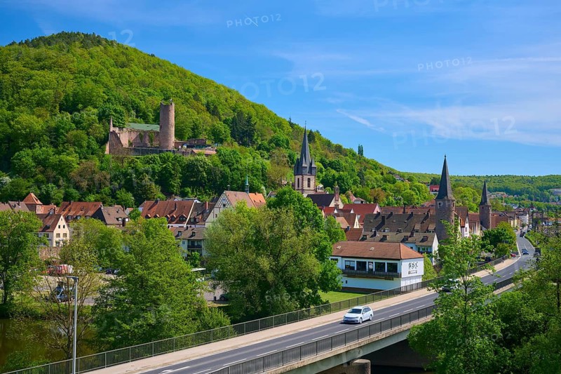 Street with bridge in a village with a hill in the background, strewn with historic buildings, Main, Gemünden am Main, Main-Spessart district, Spessart, Mainfranken, Lower Franconia, Bavaria, Germany