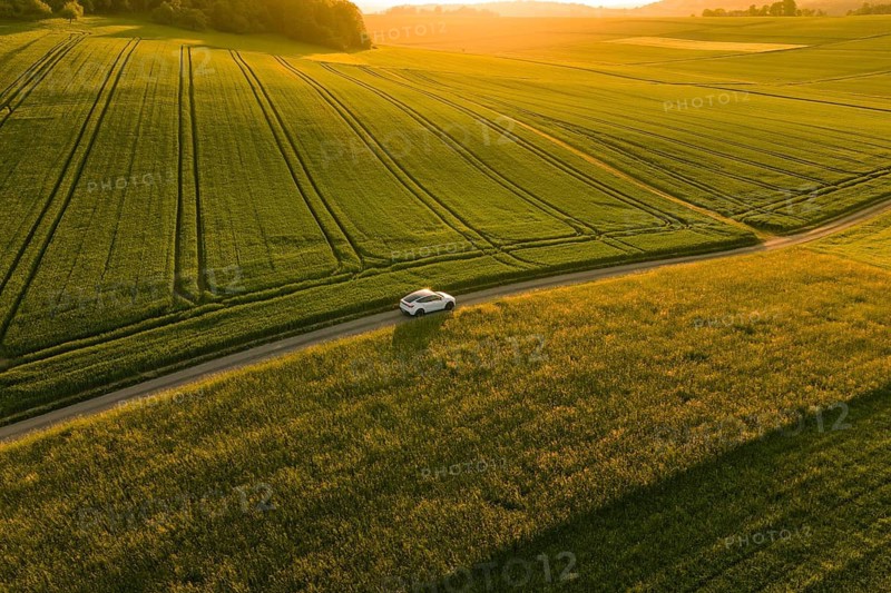 A car drives through vast fields under a calm evening sky at sunset, Tesla Model Y, Gechingen, Calw district, Germany