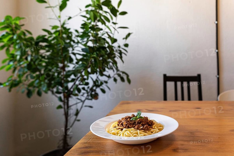 Spaghetti bolognese in a white plate on a wooden table. A classic dish of Italian cuisine
