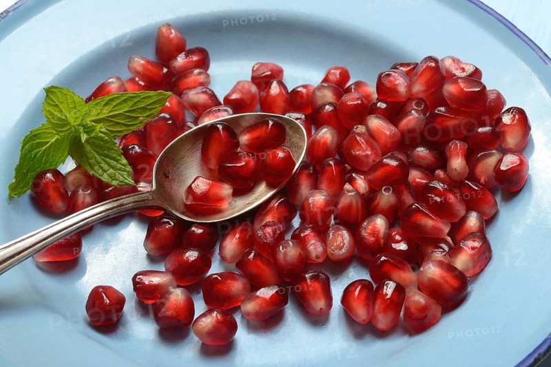 Pomegranate seeds and spoons on plate, Punica granatum