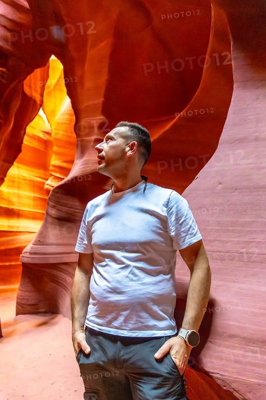 Man standing in antelope canyon looking up at the beautiful sandstone formations, experiencing the unique geological slot canyon and its vibrant colors