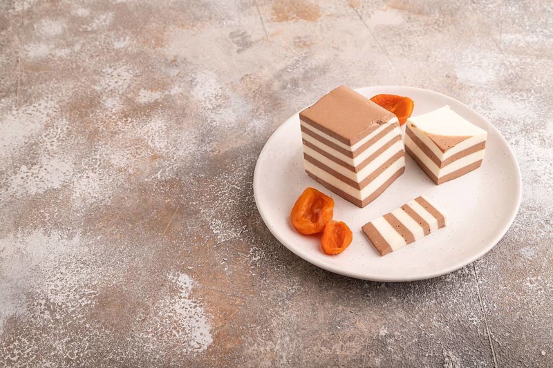 Cocoa and milk jelly with dried apricots on brown concrete background, side view, copy space, minimalism