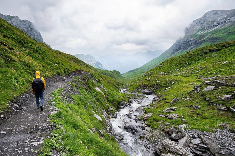 Hikers on a hiking trail on the Chilchflüh Pass in bad weather, Bergbach Sousbach, Bernese Alps, Bernese Oberland, Switzerland