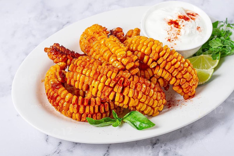 Corn ribs, with cream sauce, spices and lime, appetizer, on a white plate, homemade, no people