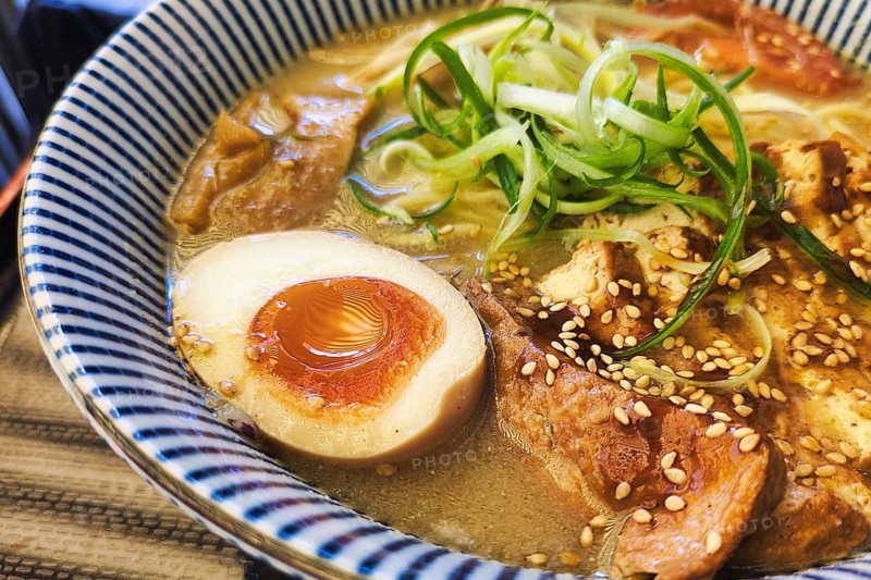 Vegetarian tofu ramen with miso broth, soft boiled egg, bamboo shoots, soybean sprouts, onions and spring onions in Japanese noodle soup