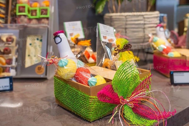 A festive gift basket with decorative chocolates and chocolate presented in a shop window conveys gift inspiration, gift basket