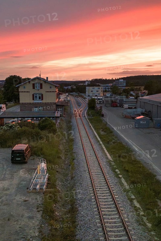 Railway tracks lead through an industrial area at sunset, sky in orange and purple, Hermann Hesse Bahn, Althengstett, Calw district, Germany