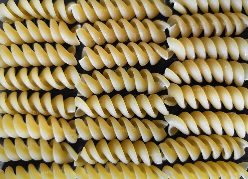 The texture of fusilli pasta on a black background. wallpaper. background. Close-up. Horizontal