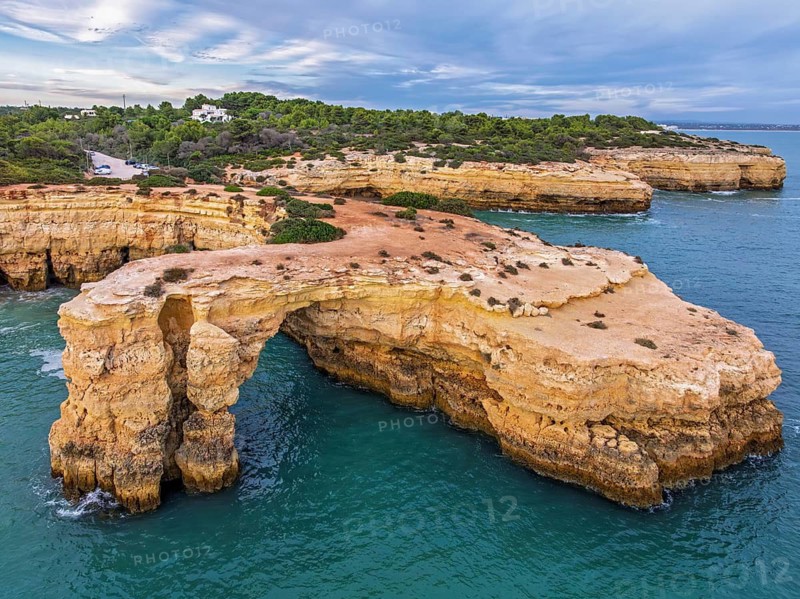 Drone view of Arco de Albandeira and Praia de Albandeira in Algarve, Portugal, with limestone cliffs, Atlantic water, sea arch, and a wide angle over the turquoise cove