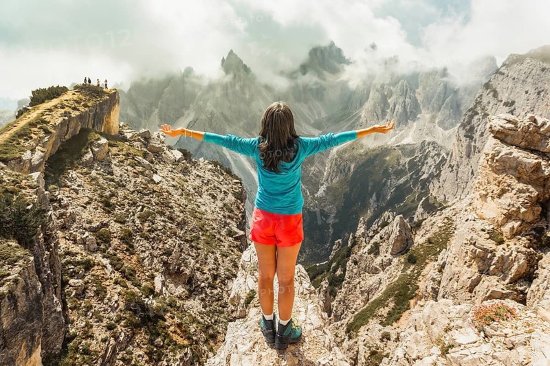 Aerial view Woman hiker on viewpoint with Open Arms Overlooking Cadini di Misurina Peaks Dolomites Italy. Unesco heritage. Tour group travel italian alps. Tourism Europe