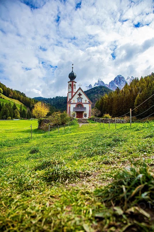 Church in alpine landscape with meadows and forests in the background, dramatic sky with clouds, Church of St. Johann in Ranui, Villnöss Valley, South Tyrol, Italy, view of a church in the Alps with an impressive mountain panorama and cloudy sky, Church of St. Johann in Ranui with Geisler Group, Villnöss Valley, South Tyrol, Italy