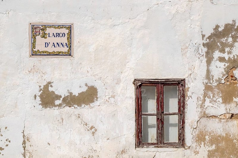 A weathered house façade with an old window and a street sign Largo d' Anna, Tavira, Portugal